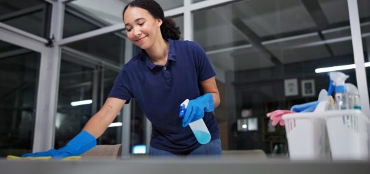Cleaner, cleaning table woman in office for fumigation, spray disinfect and safety suit from disease risk in building. Maintenance, person and chemical liquid for pest control, health and hygiene